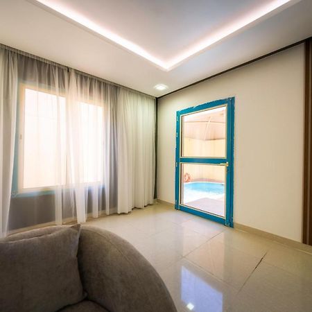 Mirada Gold Jizan - Resort & Private Pools Εξωτερικό φωτογραφία The photo shows a modern interior space that appears to be a room in a home or a building. There is a large window with sheer curtains letting in natural light, which contributes to a bright and airy atmosphere. On one side of the room, there is a sl