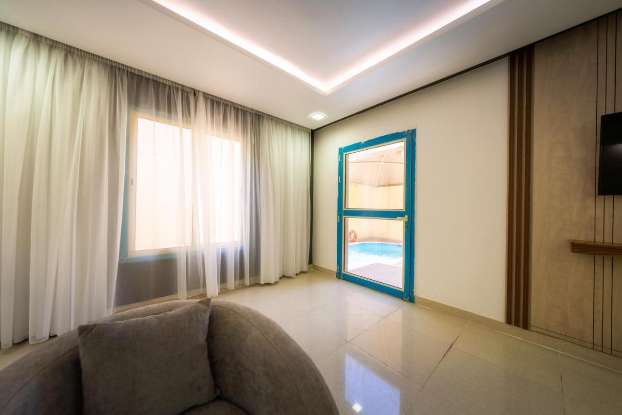 Mirada Gold Jizan - Resort & Private Pools Εξωτερικό φωτογραφία The photo shows a modern interior space that appears to be a room in a home or a building. There is a large window with sheer curtains letting in natural light, which contributes to a bright and airy atmosphere. On one side of the room, there is a sl